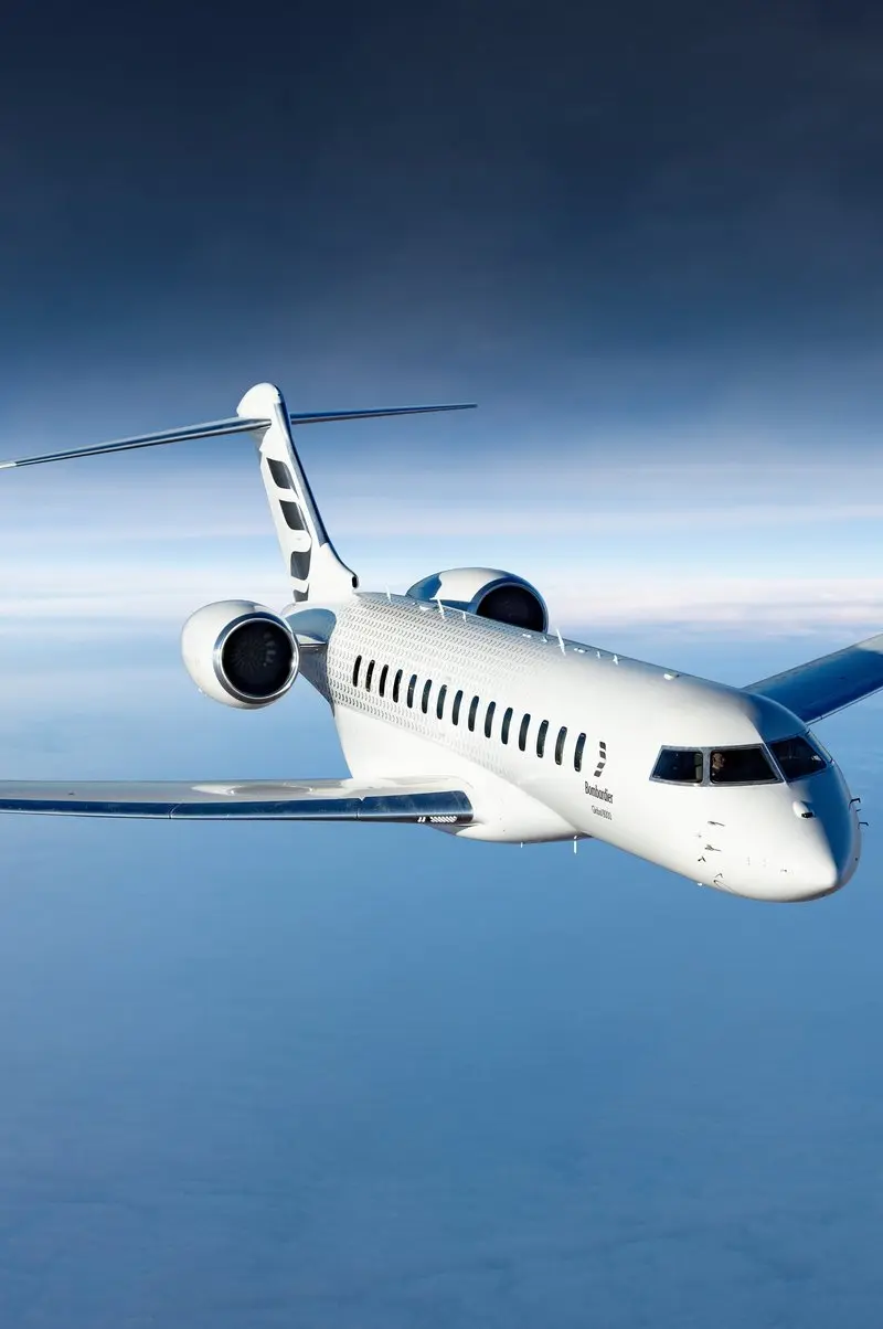 The Bombardier Global 8000 private jet flies high above the clouds with a crescent moon in the dark sky, available for charter from Marbella.