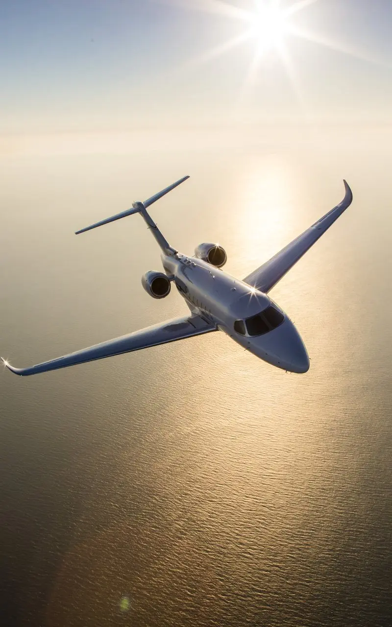Cessna Citation Longitude — Aerial sunset flight A Cessna Citation Longitude private jet soars high above the sun-drenched ocean, reflecting the golden light of sunset.