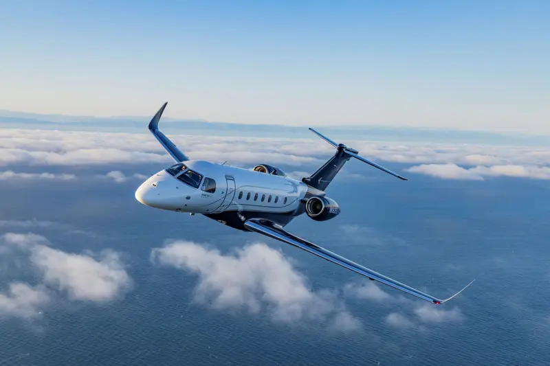 Embraer Legacy 500 — Flying above the ocean The Embraer Legacy 500 private jet flies gracefully above the clouds and ocean, showcasing its sleek design.