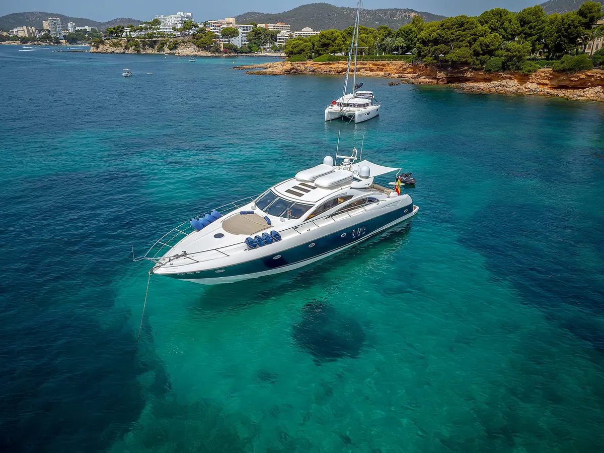 Sunseeker Predator 72 — Aerial view in Marbella The Sunseeker Predator 72 motor yacht is seen from an aerial view, anchored in the crystal-clear turquoise waters of Marbella.